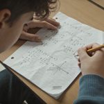 eleve assis resolvant fraction sur feuille de math