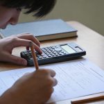 Eleve corrige un controle avec calculatrice sur bureau