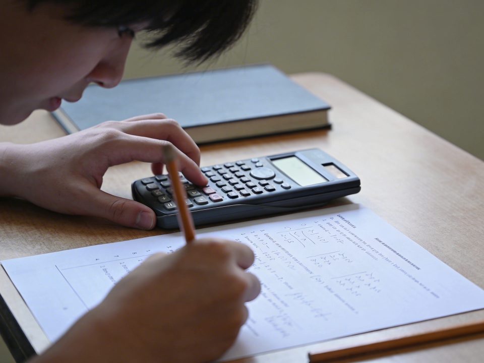 Eleve corrige un controle avec calculatrice sur bureau