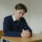 Eleve pensif assis a un bureau vide