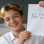 eleve souriant levant un bulletin note 16 sur 20
