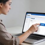 femme tapant un email outlook sur ordinateur portable
